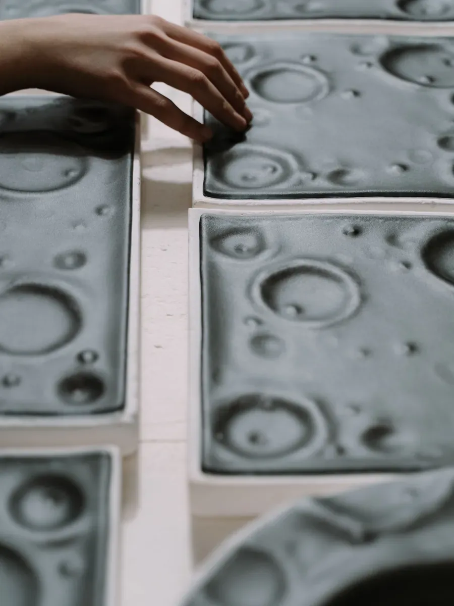 A hand inspecting freshly cast mold plates